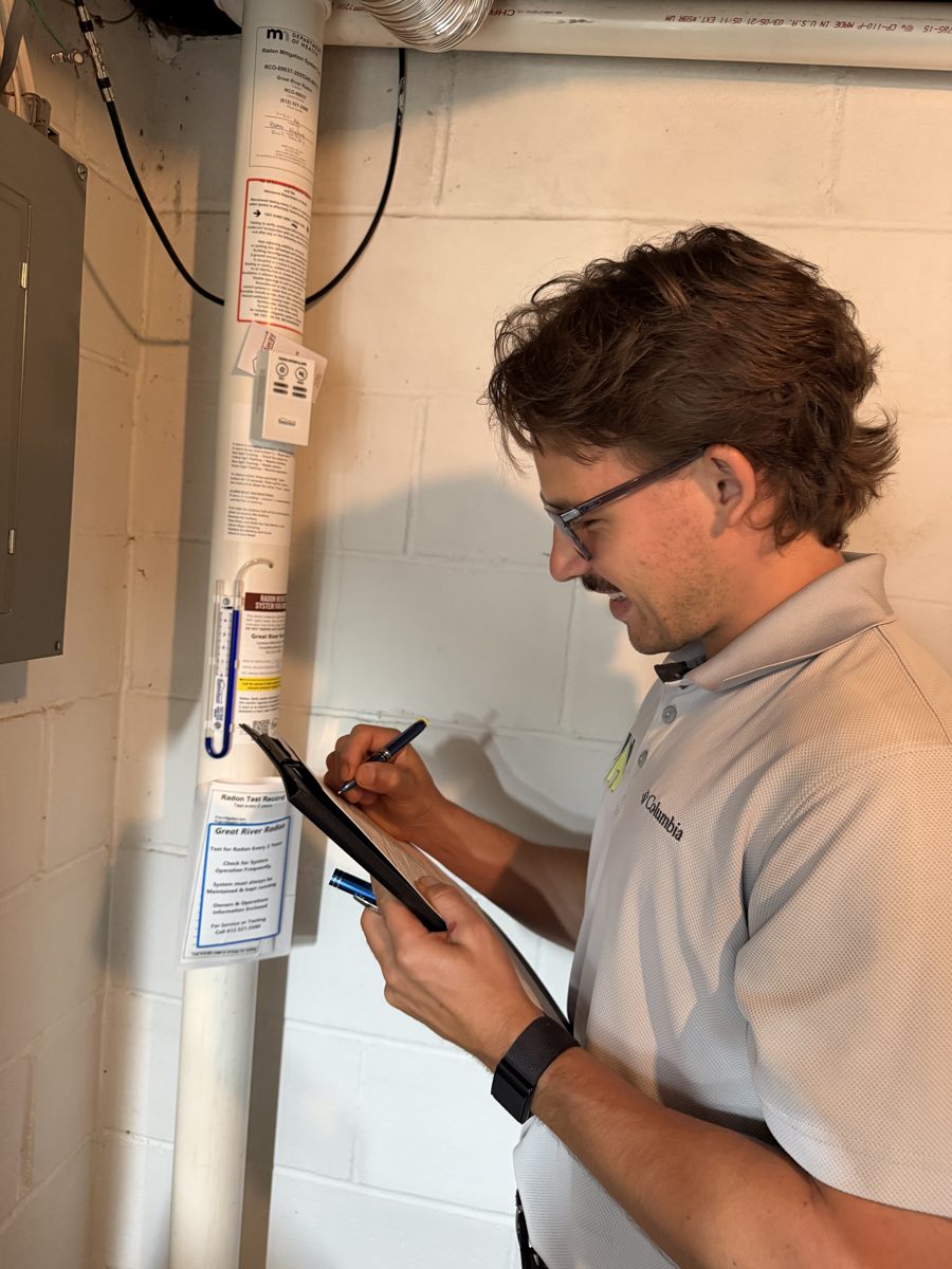 Hunter inspecting a radon mitigation system and manometer